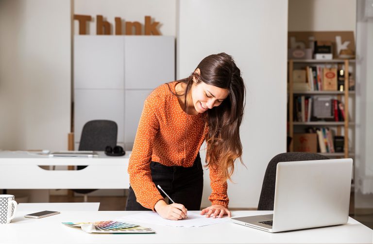 Young business woman standing in her home office writing notes.